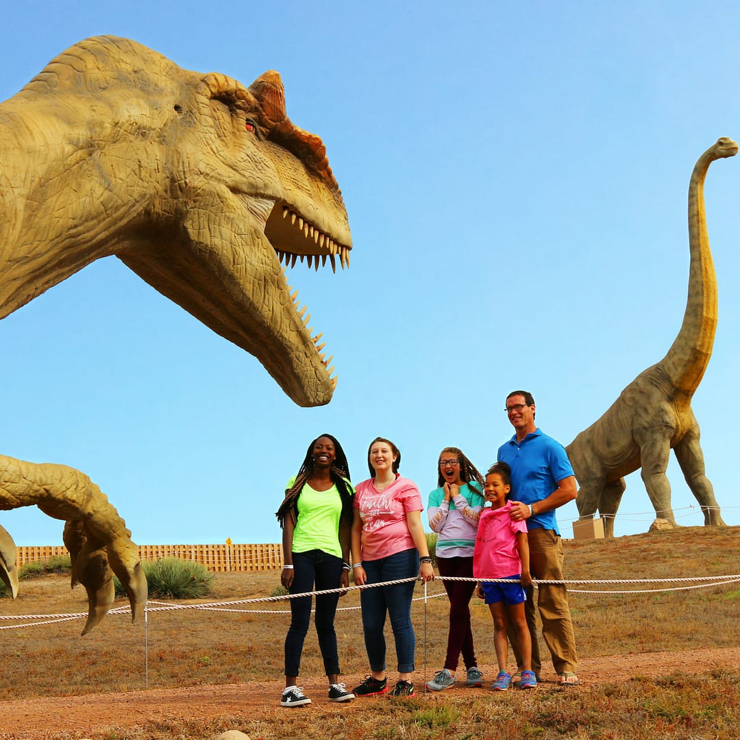 An animatronic dinosaur roars at guests passing by on the Wild Walk path