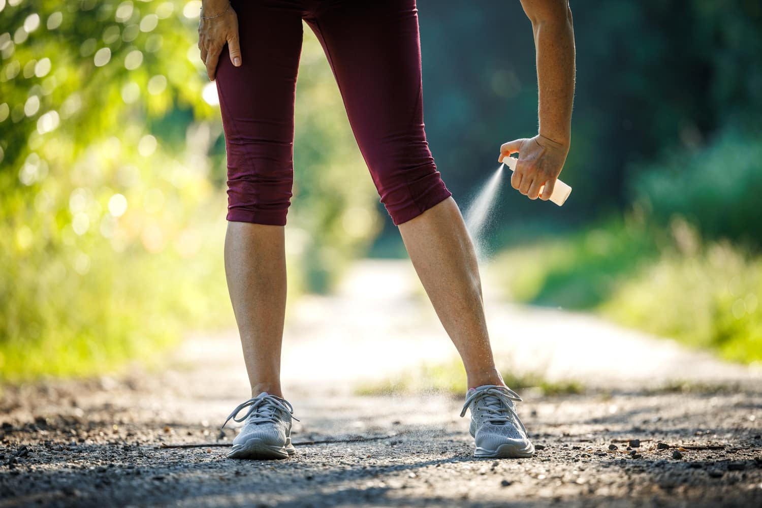 woman applying bug spray to her legs