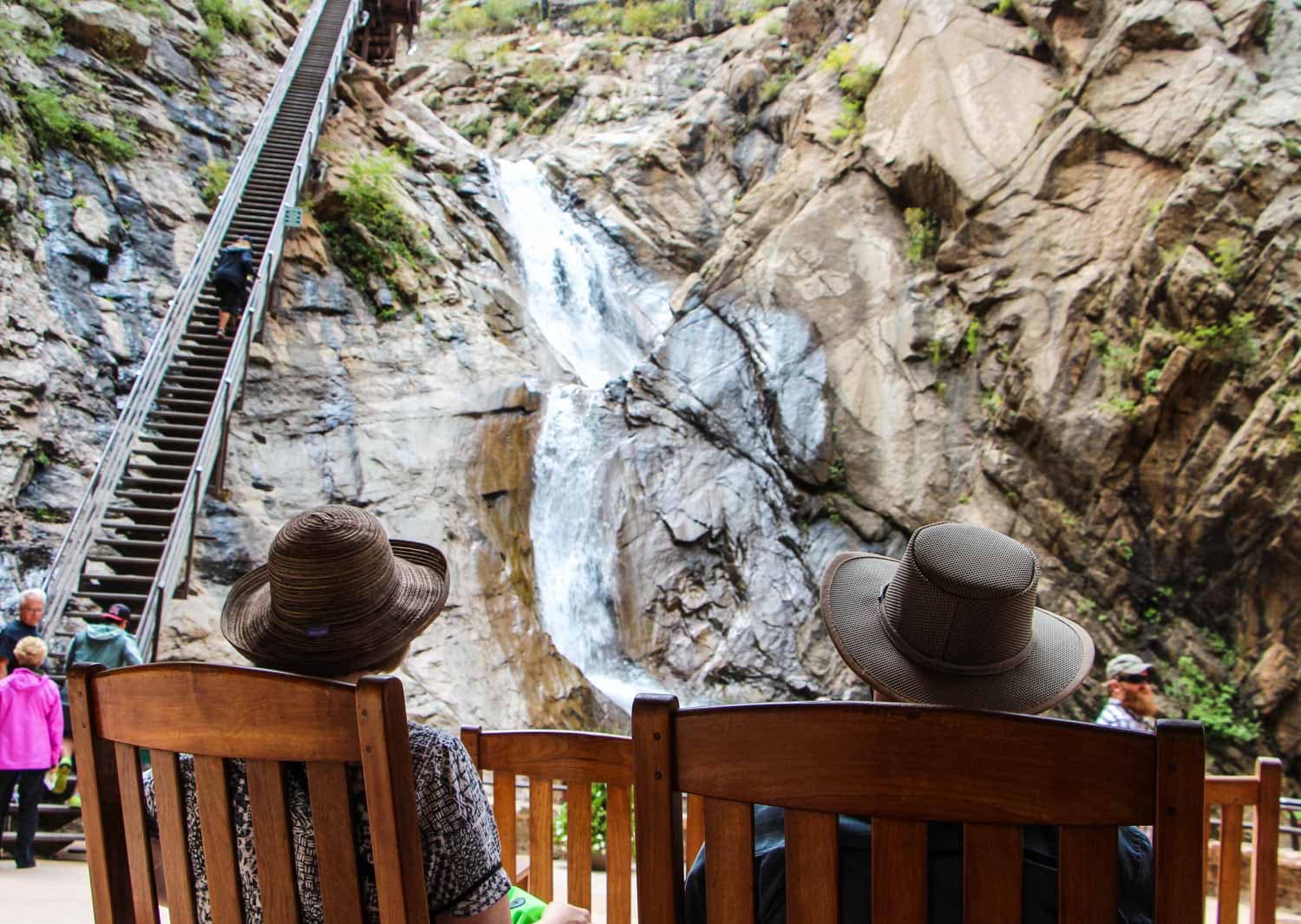Tourists Sitting On Chair At Seven Falls In Colorado Springs