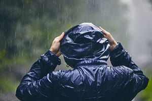person pulling rain coat hood over head