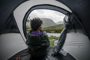 camper sitting in tent while rain falls outside