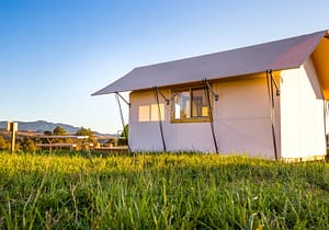 exterior view of a canvas glamping tent with green grass in foreground