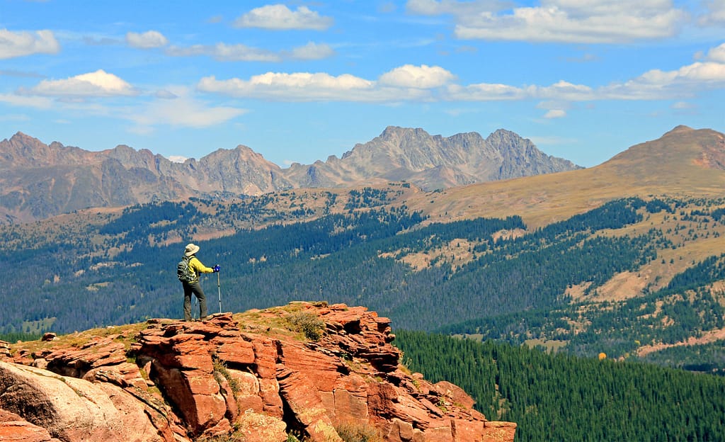 Hiker standing on rock outcropping near Vail Pass