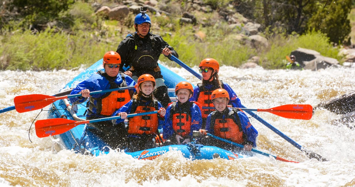 Rafters paddling through whitewater rapids on the Arkansas River in Colorado with an Echo Canyon River Expeditions guide