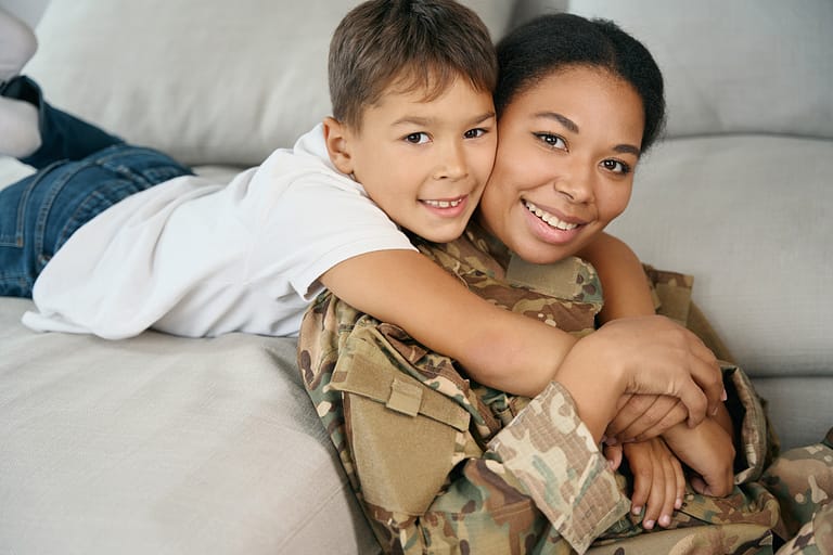 boy hugs his mom who is dressed in military uniform
