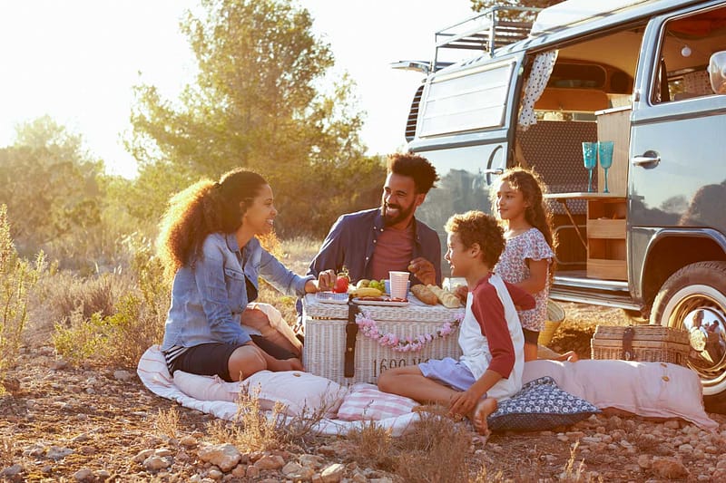 Family having a picnic next to camper van