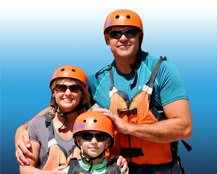 Smiling family wearing helmets and life jackets posing together before rafting.