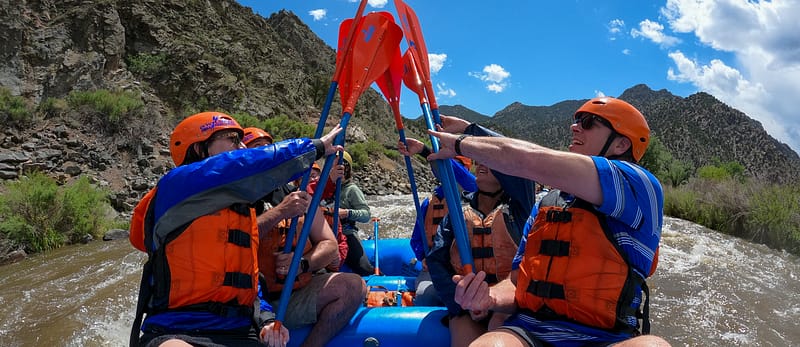 A group of rafters celebrating with a paddle high five