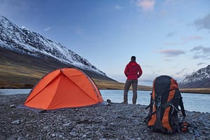 backpacker standing at lake by tent